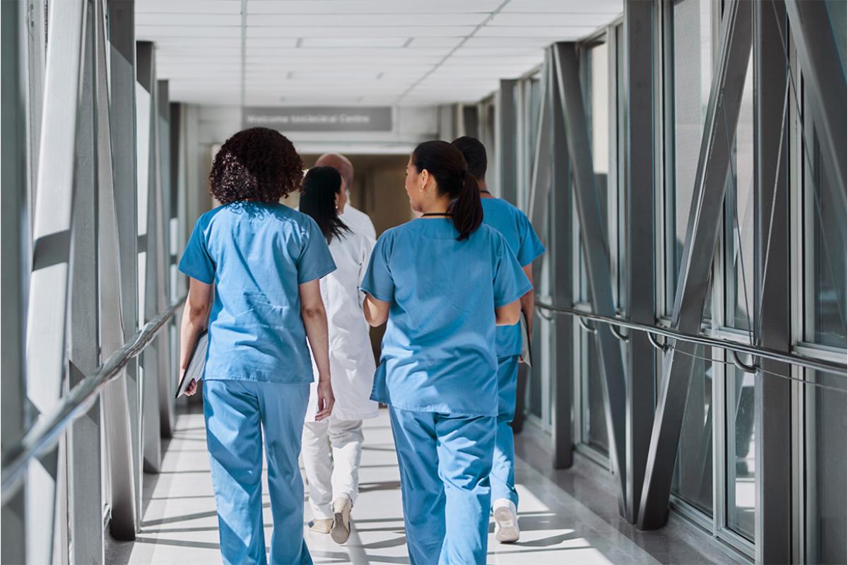 Health care workers walking with colleagues in hospital corridor