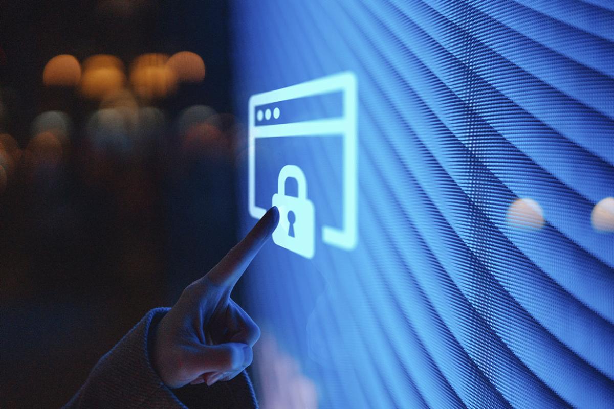 Hand touching illuminated digital screen displaying a locked sign