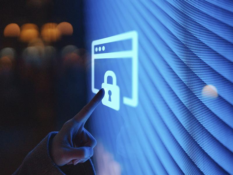Hand touching illuminated digital screen displaying a locked sign