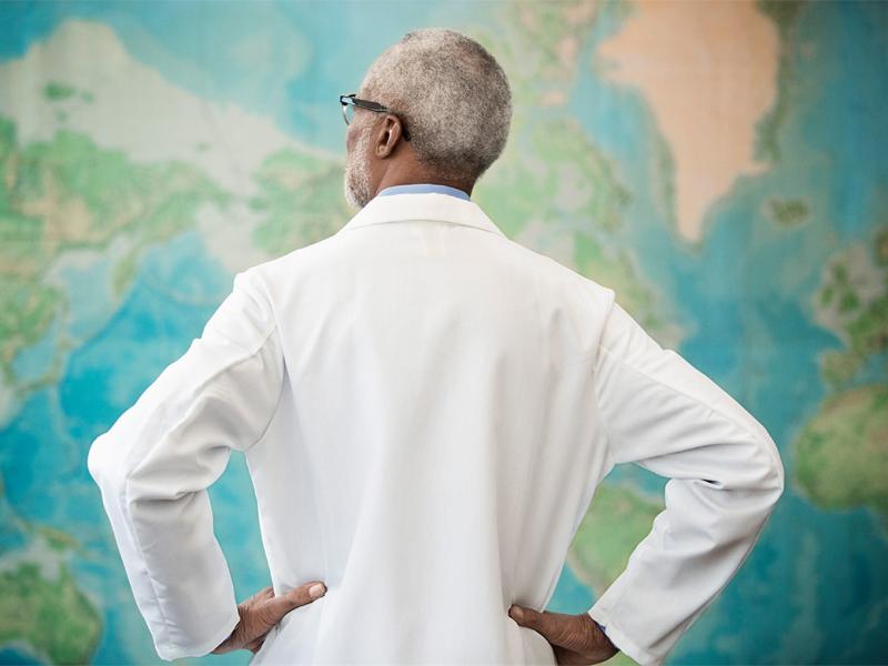 Physician standing in front of a world map