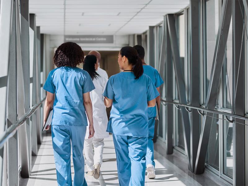 Health care workers walking with colleagues in hospital corridor