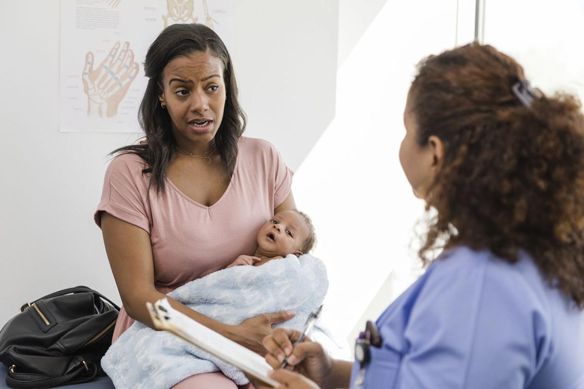 Mother holding infant in conversation with a physician