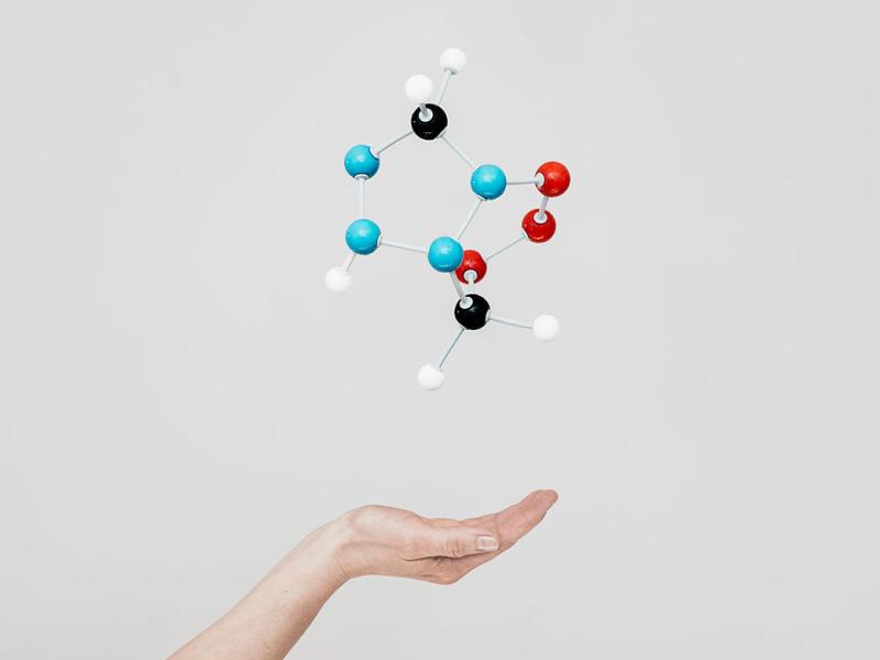 Model of molecules floating above person's hand