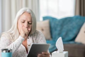 Coughing woman looking at a digital tablet