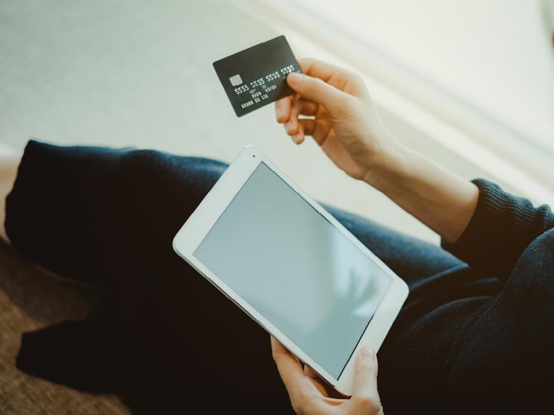 Person holding credit card and tablet computer