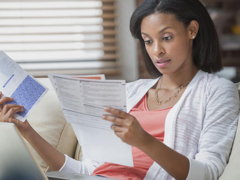 Woman sitting on couch looking at bills