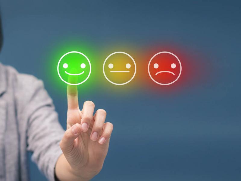 Person touching a screen of 'rate your satisfaction' smileys