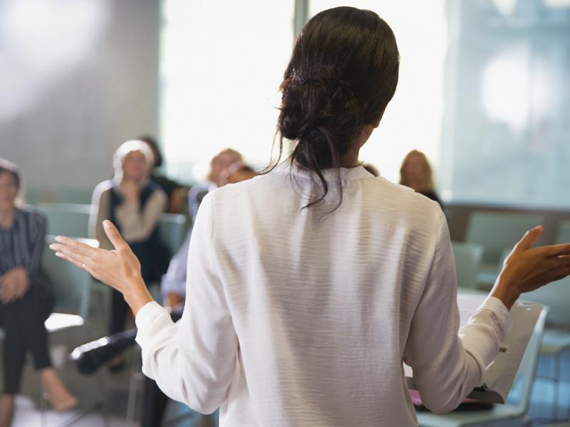 Background view of a woman giving a speech to a room of people