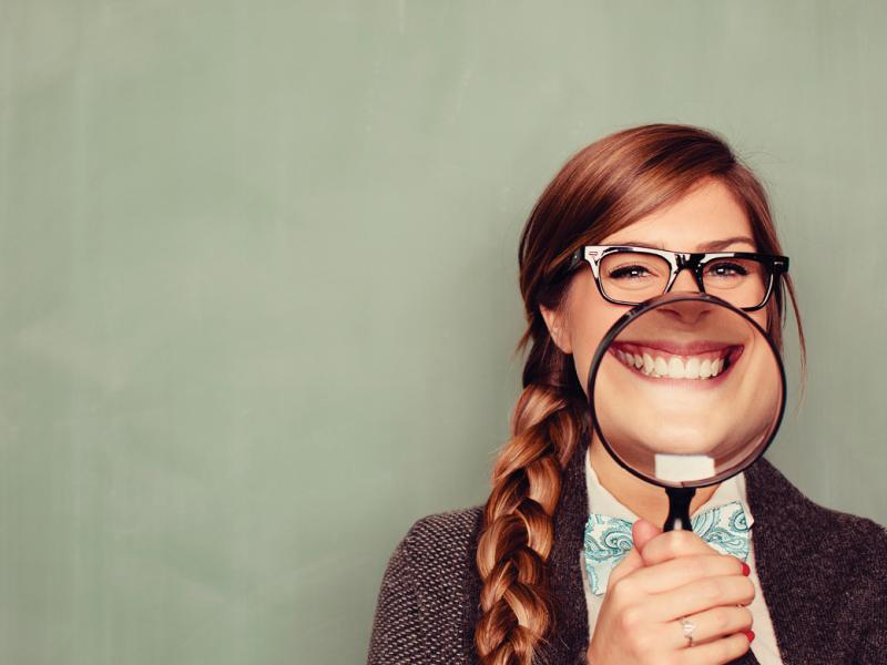 Woman smiling behind magnifying glass