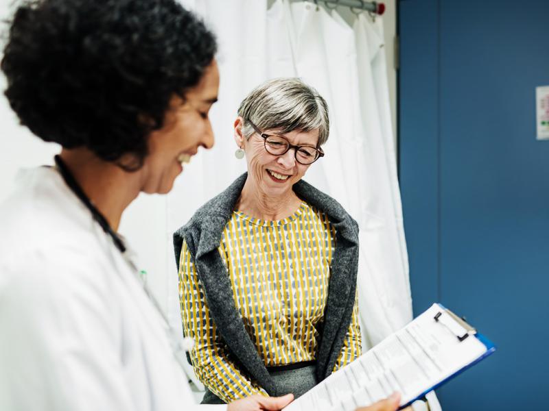 Smiling senior patient and physician reviewing patient chart