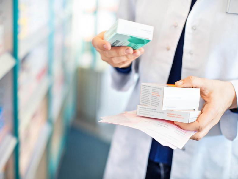 Tight shot of pharmacist reading text on prescription box