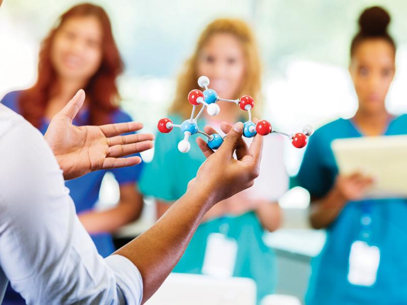 Man holding an atom model to teach residents