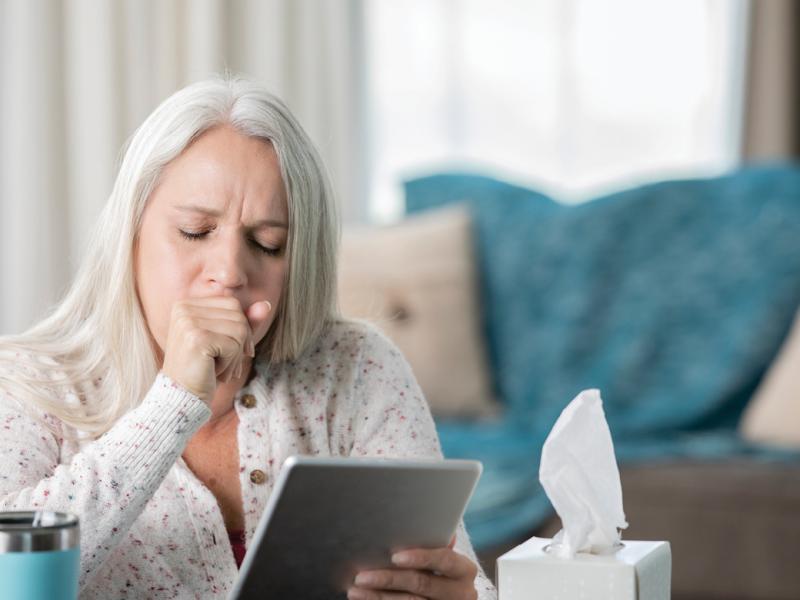 Coughing woman looking at a digital tablet