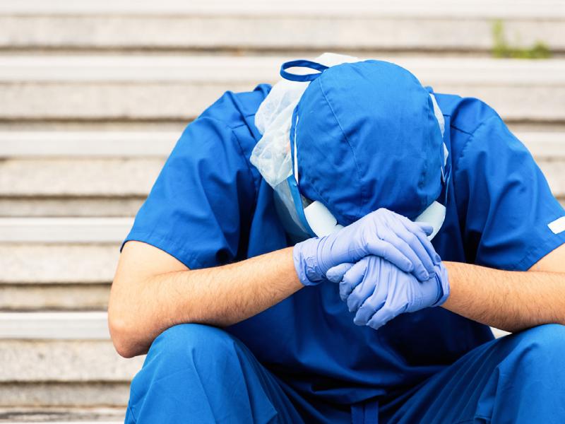 Health care worker holding head in hands