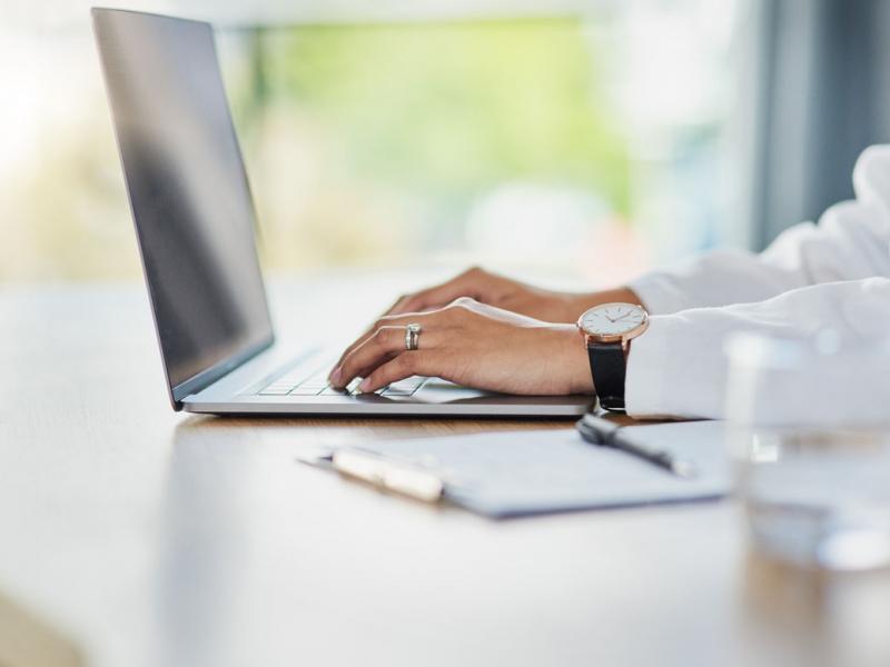 Tight shot of physcian's hands typing on laptop keyboard