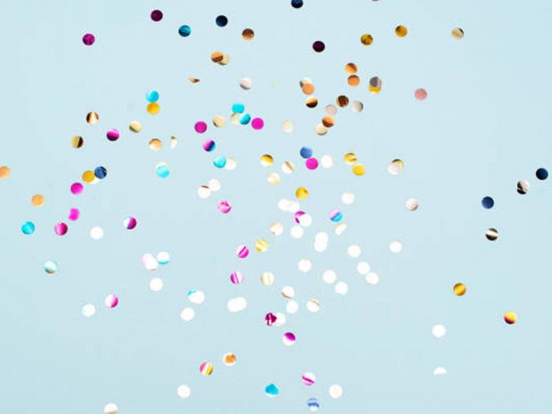 Different colors of confetti against a blue background.