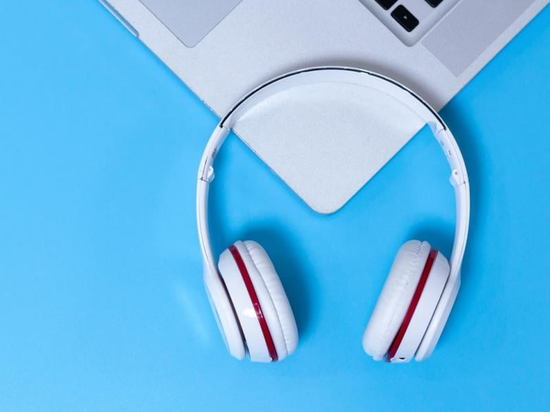 Laptop and headphones against blue background