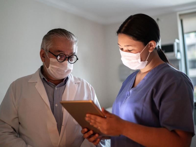 Physician and assistant looking at tablet