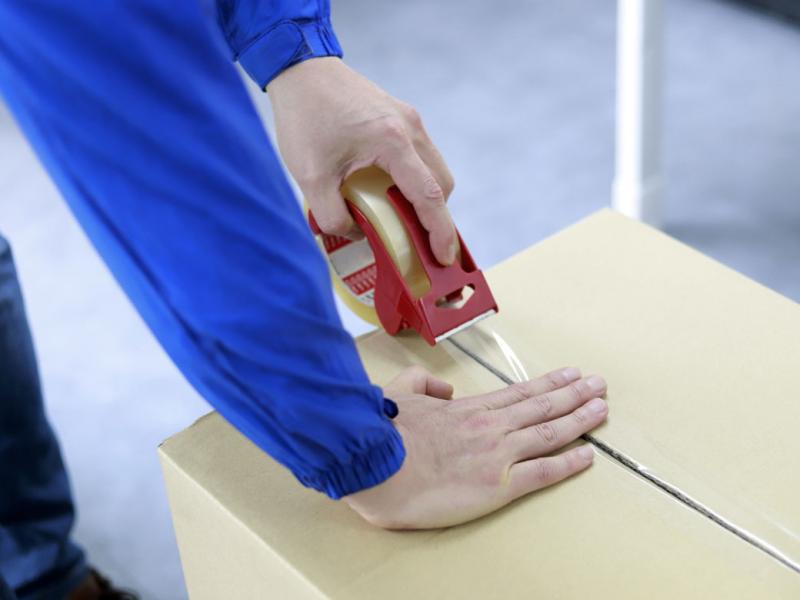 Close-up of a pair of hands taping a box shut.