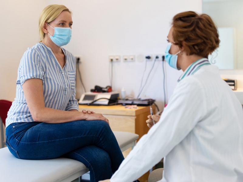 Patient with a mask being examined by physician