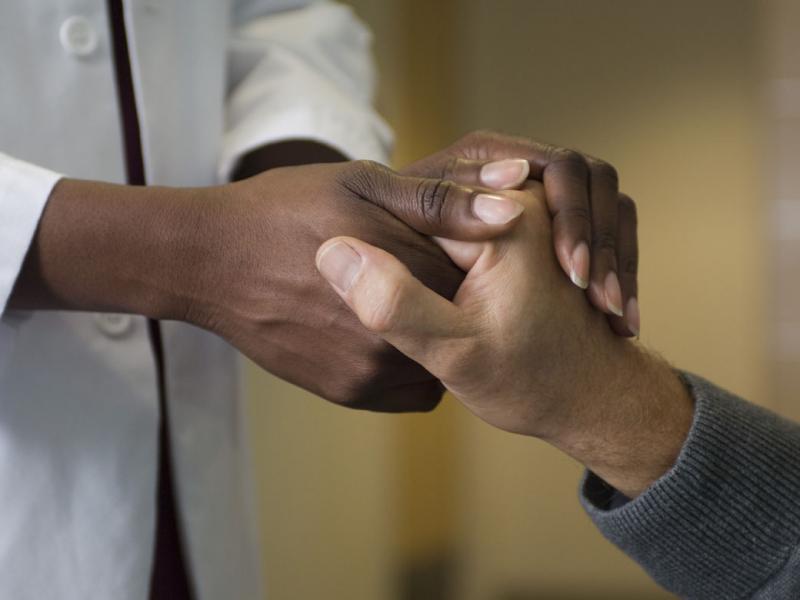 Closeup of a physician holding someone's hand