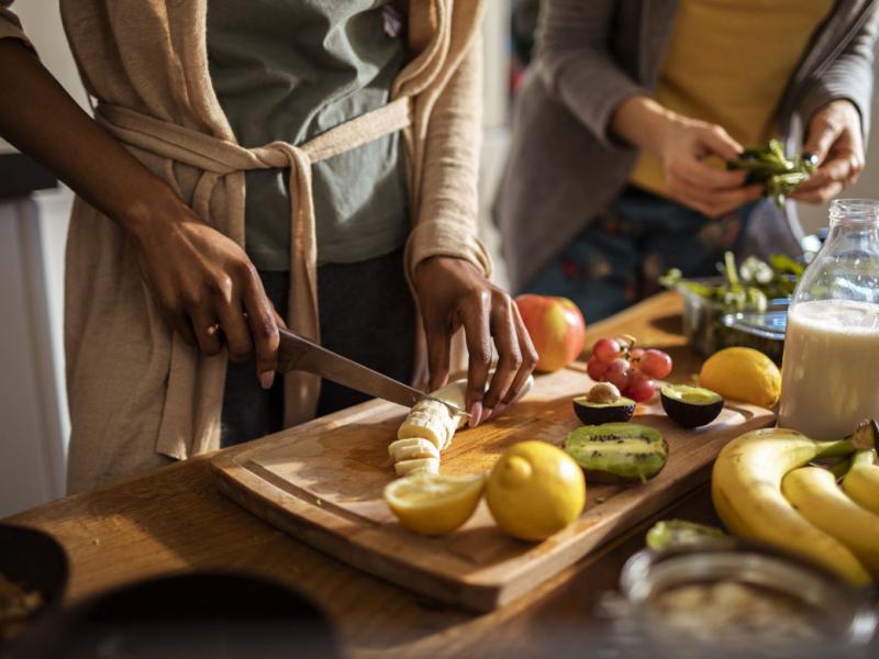 People cutting fruit in a kitchen