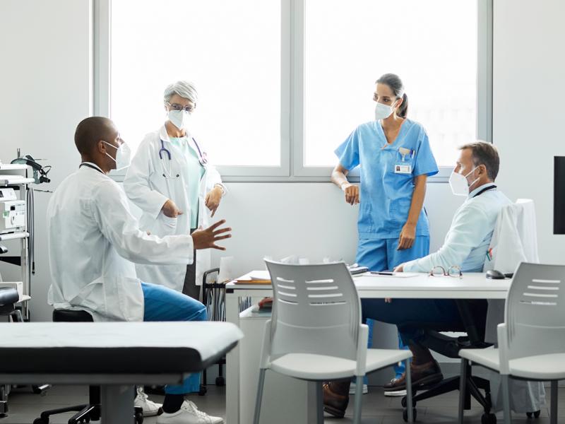 Four health care professionals having a meeting in a brightly lit hospital office.