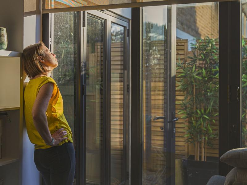Person with eyes closed, leaning against a bookshelf