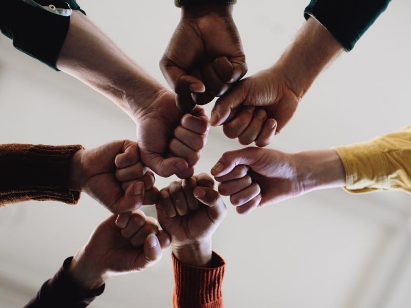 Tight shot of a group of people joining fists in solidarity
