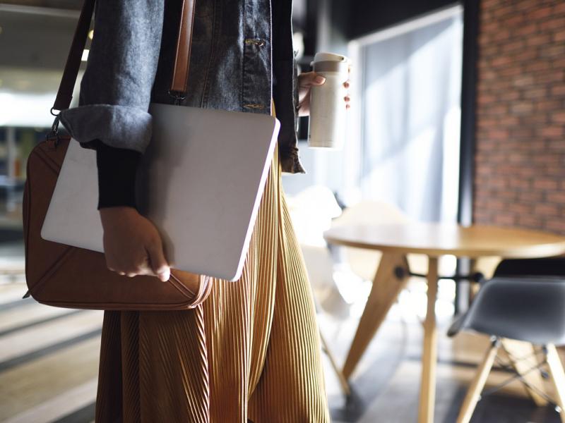 Woman carrying laptop, shoulder purse and beverage cup