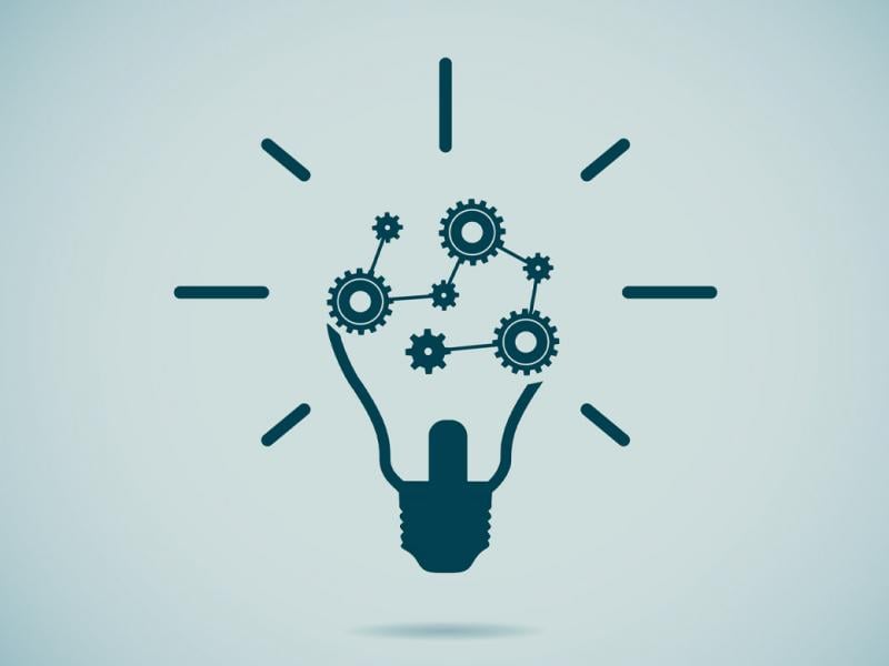 Illustration of a dark grey lightbulb, with the inner workings replaced by a series of gears.