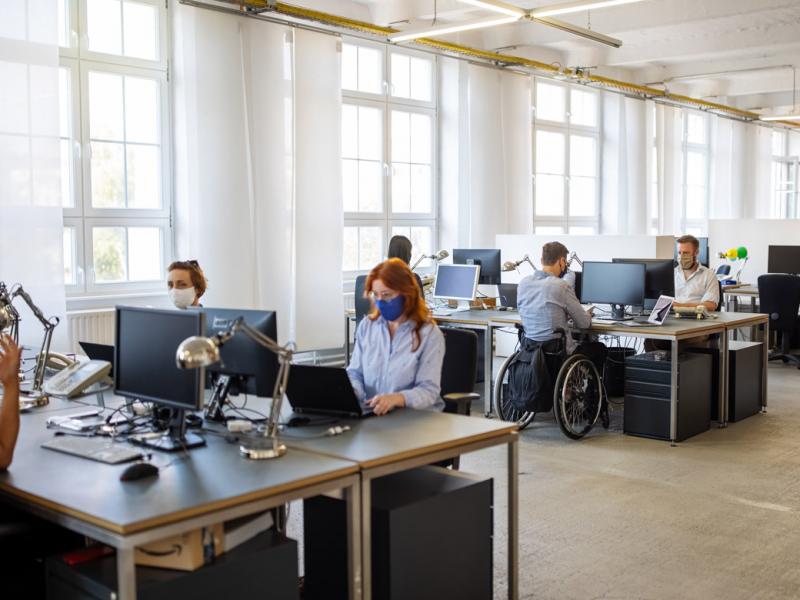 Group of people in an open office wearing masks and working on their computers