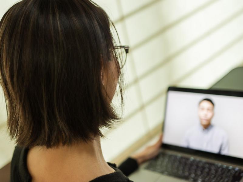 Back head of young woman on a laptop participating in a virtual interview