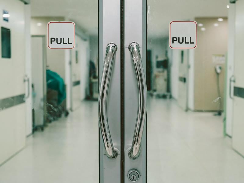 Closed glass doors with a "pull" sign leading to an operating room area
