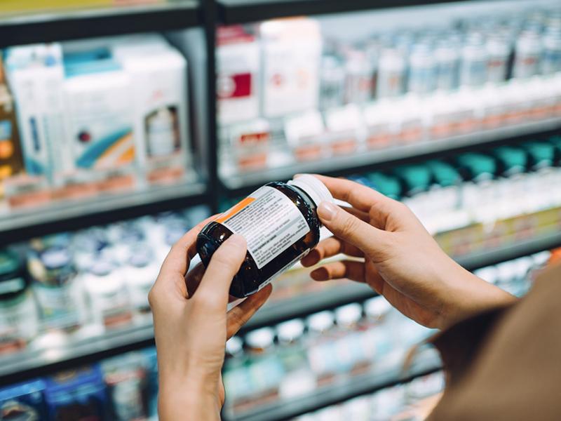 Tight shot of person reading label on vitamin or supplement bottle