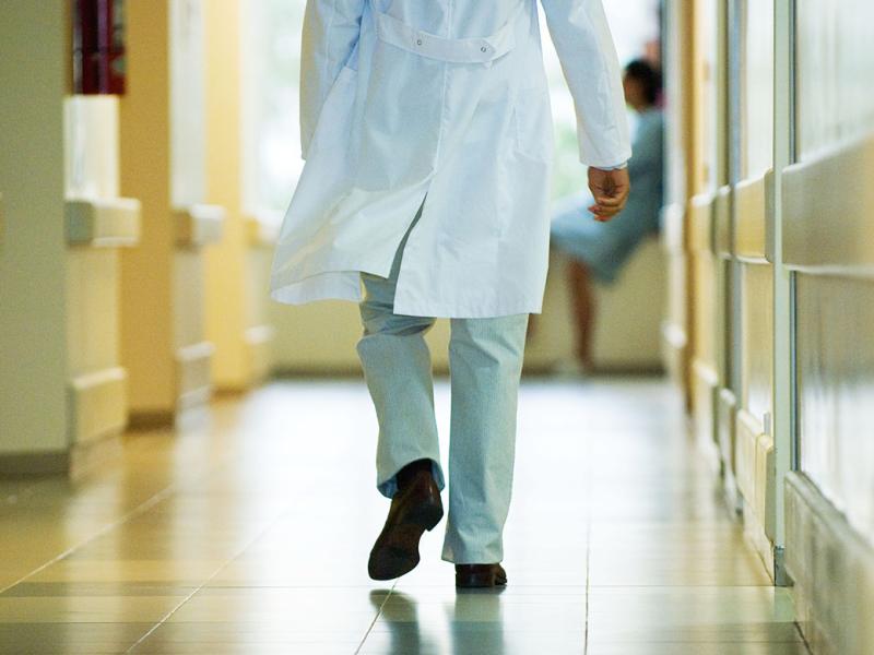 Back shot of a physician in a hurry walking down a hospital hallway
