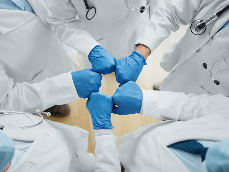 Group of health care workers bumping gloved fists