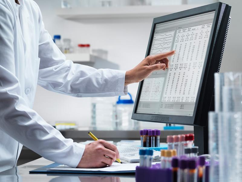Health care worker at computer and pointing at screen