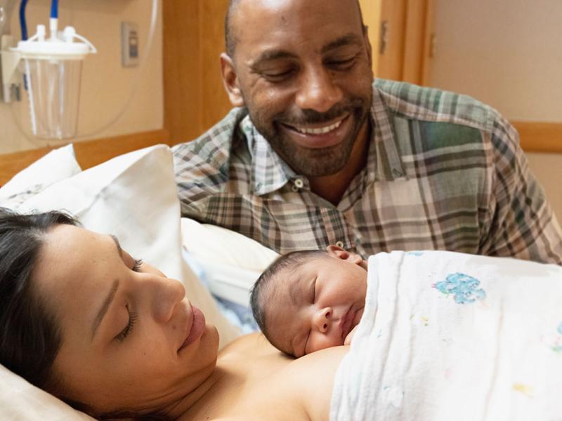 Smiling family cradling a newborn baby