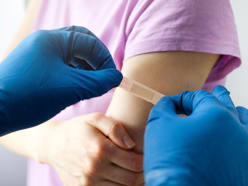 Health care worker putting bandage on child's arm