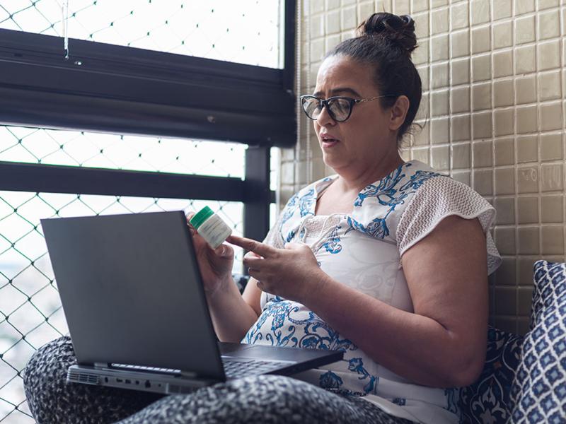 Person looking at prescription bottle in front of laptop
