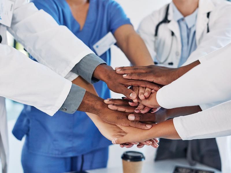 Group of medical practitioners joining their hands together in a huddle