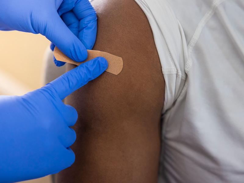 Health care professional applying adhesive bandage to person's upper arm