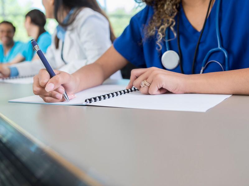 Health care professional writing in a notebook