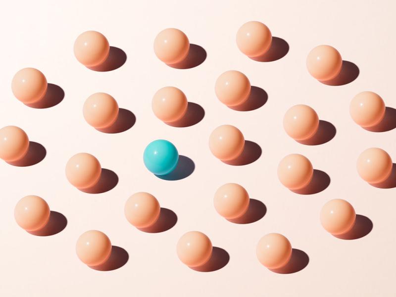 Turquoise colored sphere among peach colored spheres