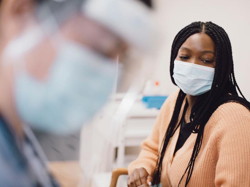 Patient in a physician's office with physician in foreground