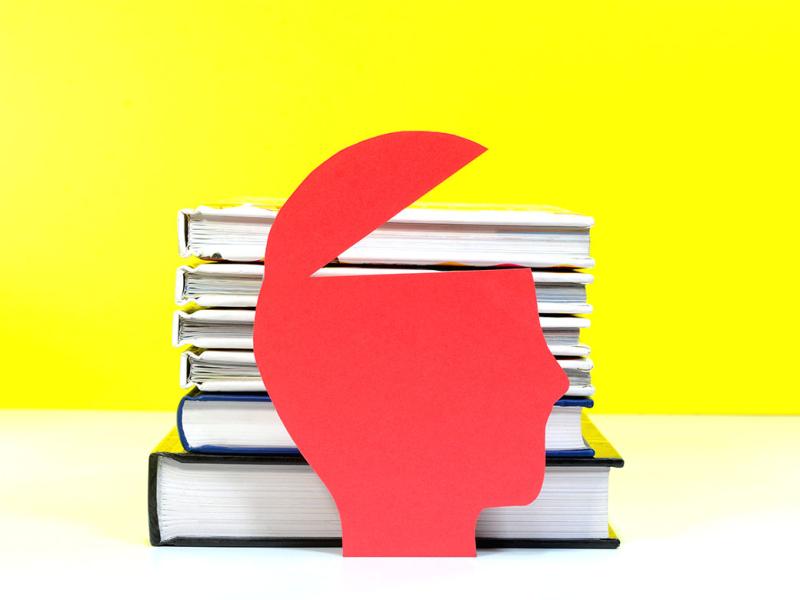 A model of a open head in front of a stack of books