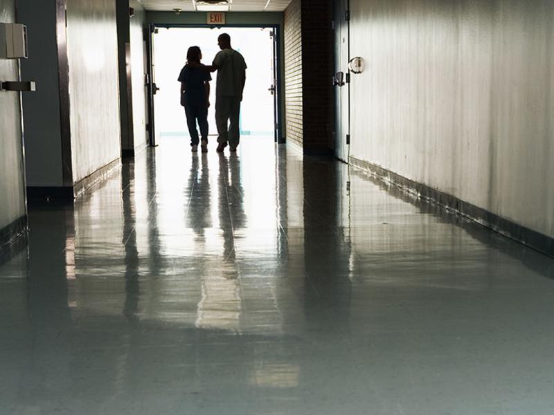Two figures walking down a hallway