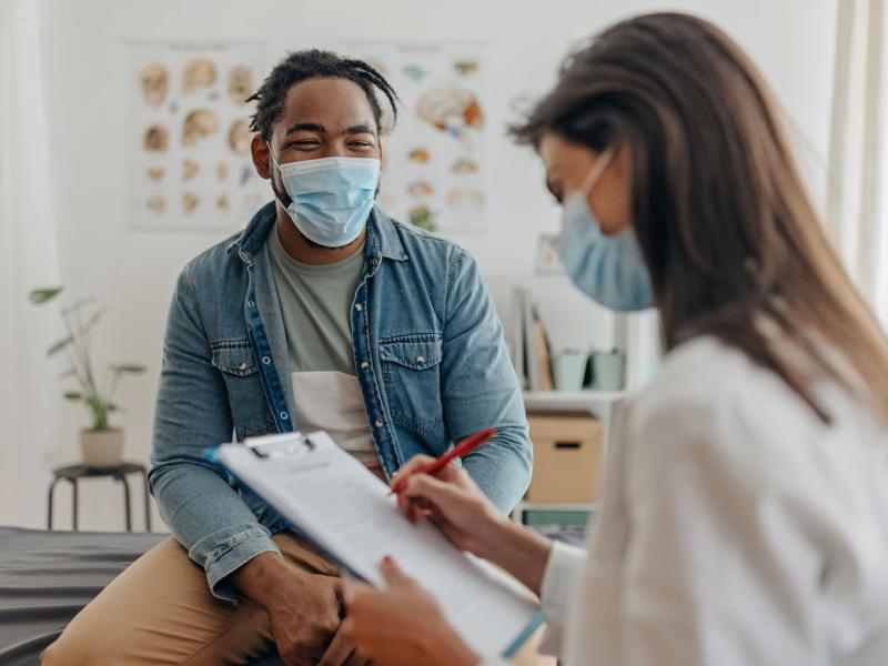 Physician taking notes while talking to patient
