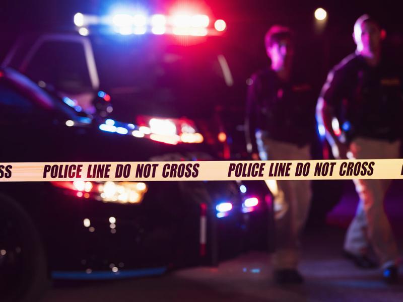 Crime scene yellow tape with police in background